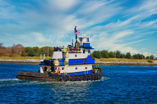 An industrial blue tugboat heads east on the Cape Cod canal on November morning,