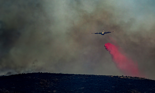 Air plane dumping fire retardant on a brush fire