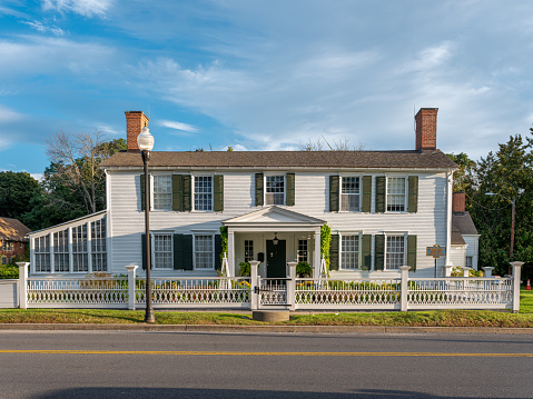 Picture of Kent-Delord House Museum on a beautiful summer morning. The sky is blue with white clouds. This Plattsburgh museum is popular.