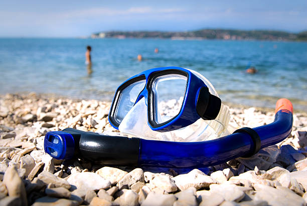 Blue diving goggles on sea beach stock photo