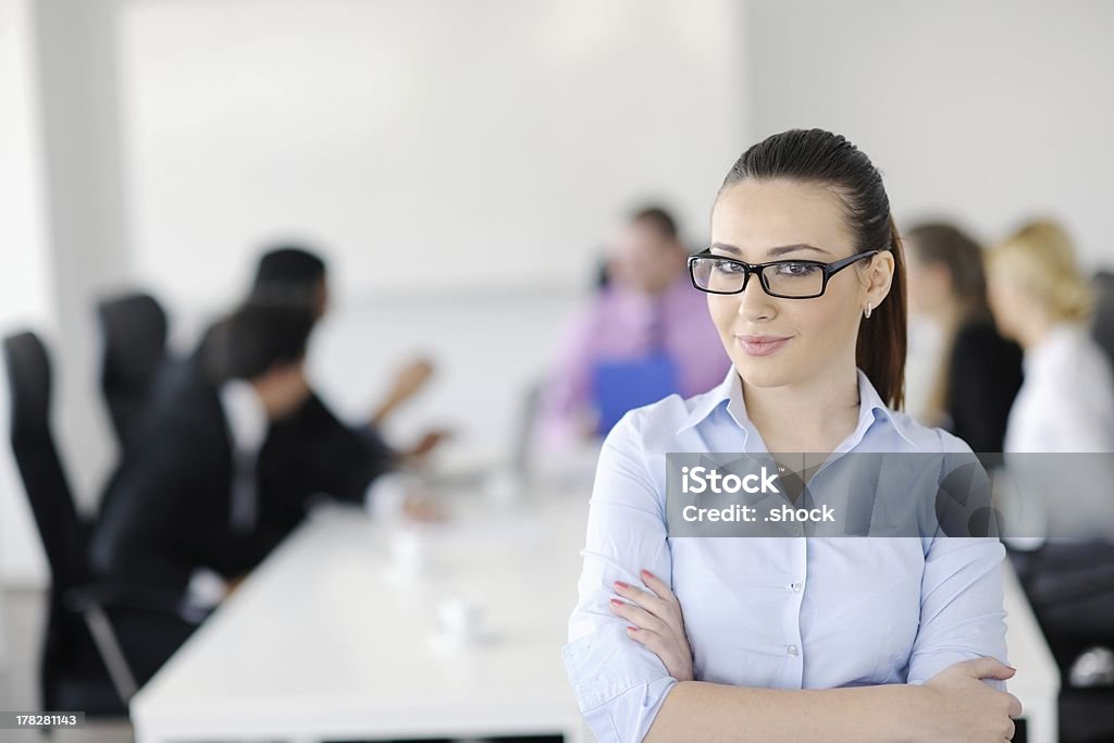 business woman standing with her staff in background Successful business woman standing with her staff in background at modern bright office Adult Stock Photo