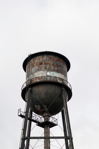 An old water tower covered with rust and graffiti.