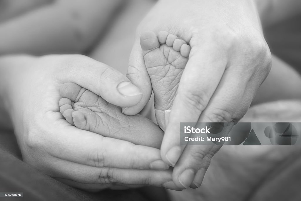 Holding Baby Feet Mom holds her newborn baby's feet black and white Premature Stock Photo