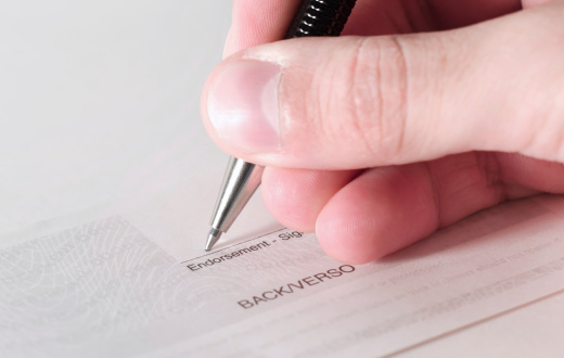 A business person signing the back of a cheque.