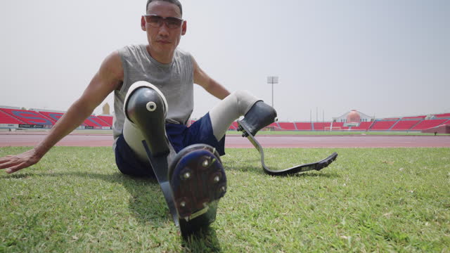 young man with above knee leg prosthesis or prosthetic exercise at running track.Stretching muscles For preparing before running a race.