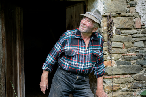 simple farmer looks searchingly out the front door
