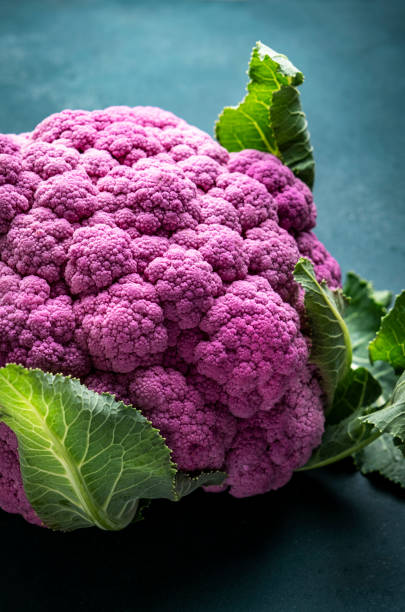 istock Fresh organic purple cauliflower cabbage with leaves on old rustic green table background, top view 1782834011