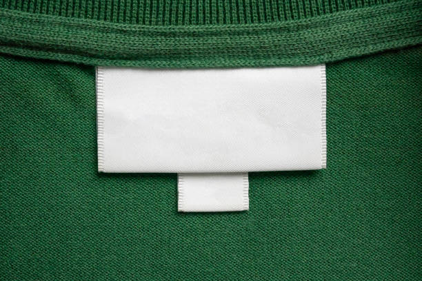 blank white laundry care clothes label on green shirt fabric texture background - scale industry copy space special imagens e fotografias de stock