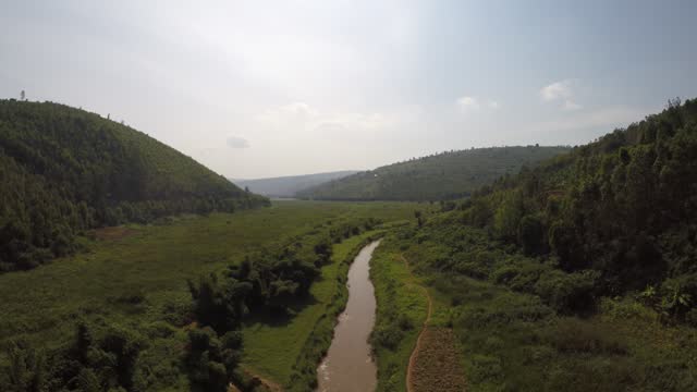 Aerial over muddy river in remote jungle mountains of Rwanda, Africa