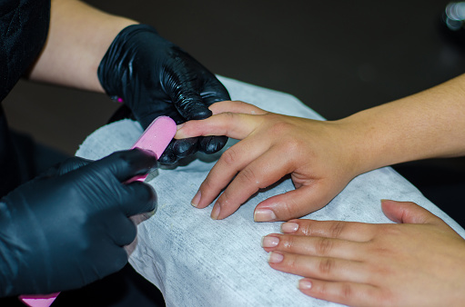 close up of filing nails in manicure procedure at beauty salon