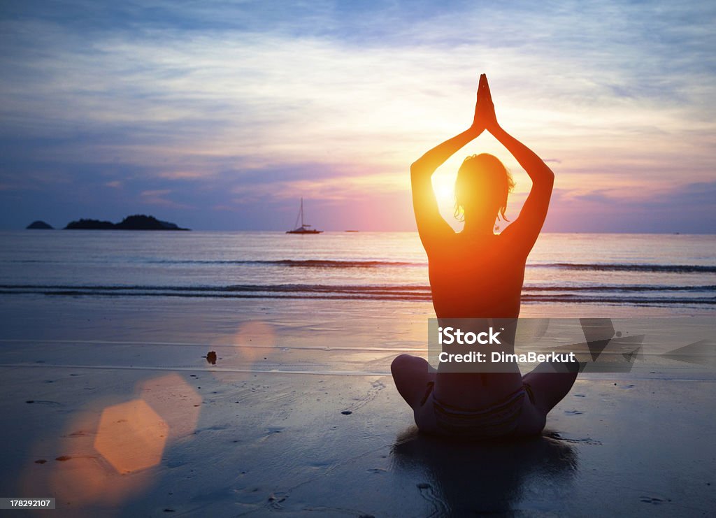 Silhouette young woman practicing yoga Silhouette young woman practicing yoga on the beach at sunset. Abstract Stock Photo