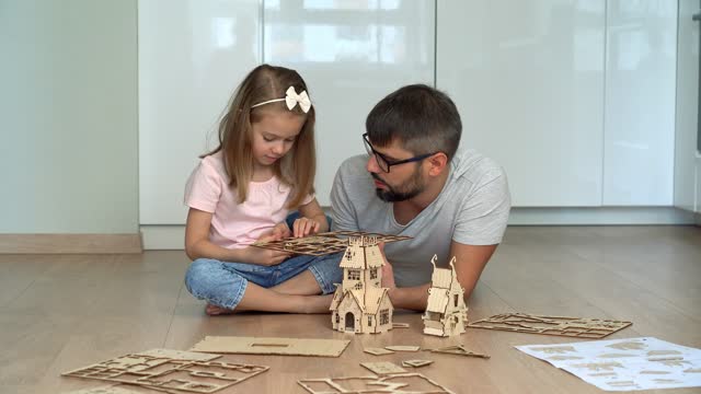 Family build wooden construction set. Father and daughter play construction kit