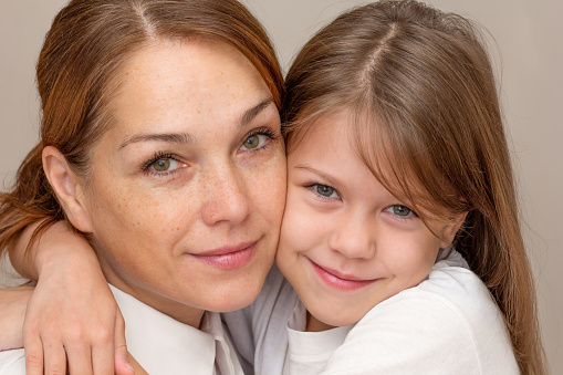 Portrait of mother and daughter hugging and looking at camera