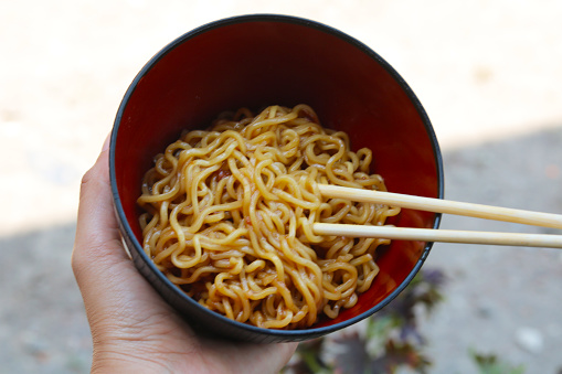 instant fried noodles in a bowl with noodles lifted with chopsticks