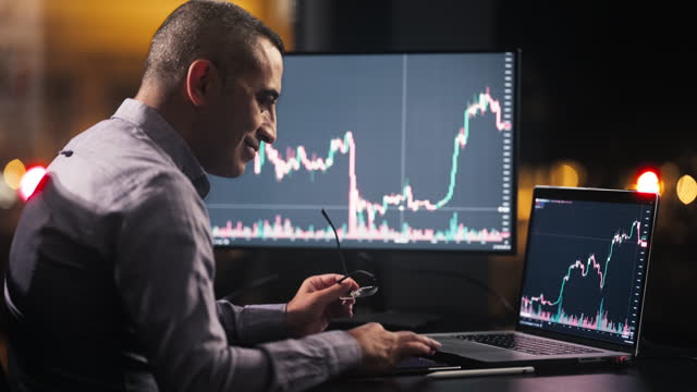 Man Checking His Stock Market Exchange Investment Using His Laptop Computer At Night