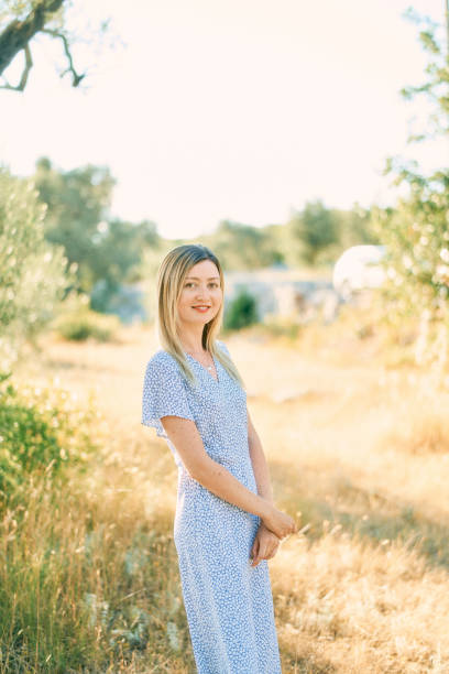 young woman stands on a sunny lawn with her hands folded in front of her - 13448 imagens e fotografias de stock