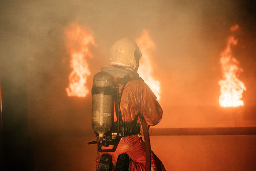 Firefighters using fire hose extinguishing burning fire in building