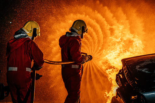 2 firefighters spraying water fire fighting operation