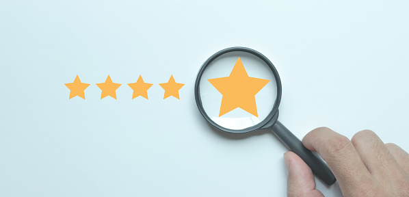 Yellow star inside a magnifying glass on a white background to focus on customer satisfaction and product service evaluation concept.