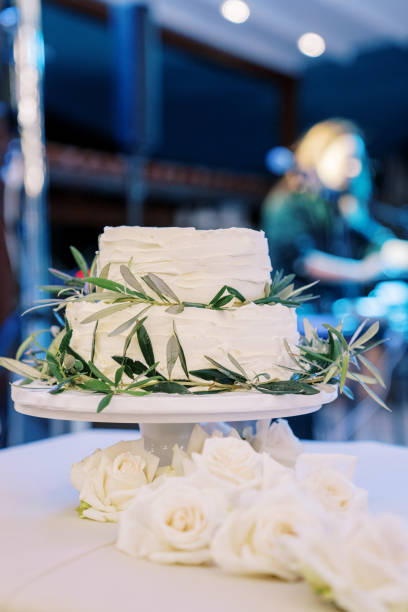 istock Wedding cake decorated with green olive branches stands on a tray on the table 1783086968