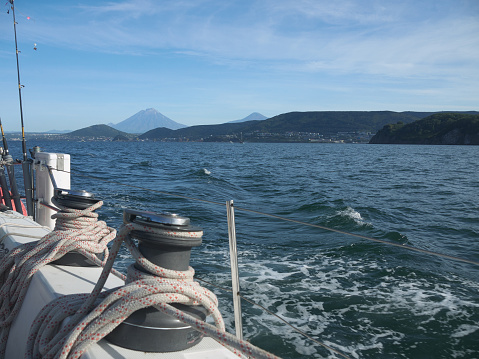 Yachting on Kamchatka, sail ship side with rigging on clew winches and mountains with Koryaksky and Avachinsky volcanoes on the coast
