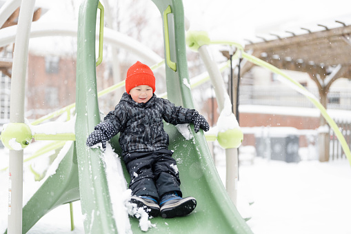 Brothers Sliding in the Snow Outdoors in Winter. They are smiling and having a lot of fun.