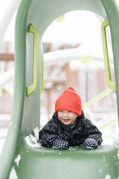 Brothers Sliding in the Snow Outdoors in Winter. They are smiling and having a lot of fun.