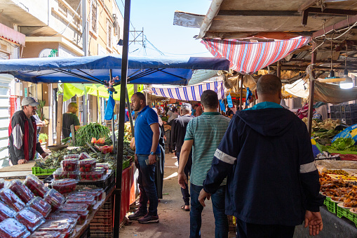 Oran, Algeria, Boudjelal Yahia street, 04 26 2023 : beautiful and colorful market scene. Algerian men walking, vendors selling goods, customers buying vegetables and fruits.