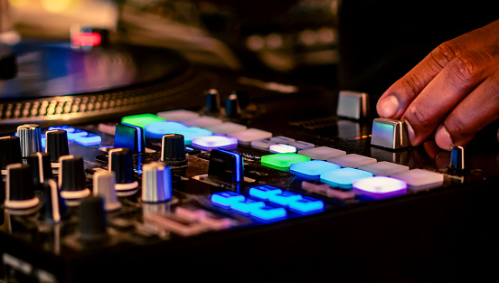 View of a DJ's hand mixing while entertaining a crowd with great music with colorful turntable