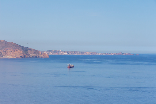 Minimalist blue panorama of the bay of Oran, Algeria. Blue sky, blue sea, a unique cargo boat.