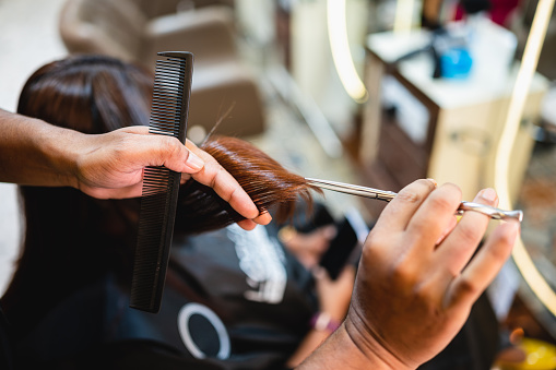 Closeup Of Hairdresser's Trimming Split Ends On Female Hair In Salon