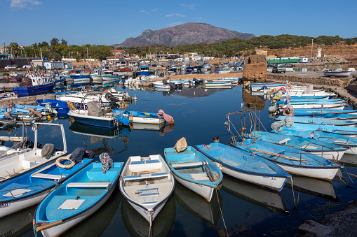 Tipaza (Tipasa), Algeria, April 23 2023 : beautiful panoramic view of the old port, with fishing boats, mountains in the background and blue sky.