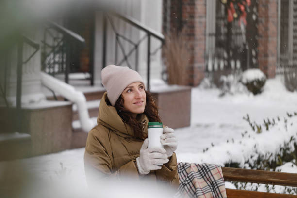 istock smiling woman drinking hot beverage from thermos flask outdoors in winter 1783229501