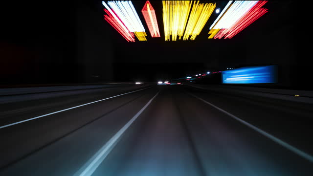 Fast Car Drive Through City at Night in Rays of Street Lights Timelapse. Windshield View.