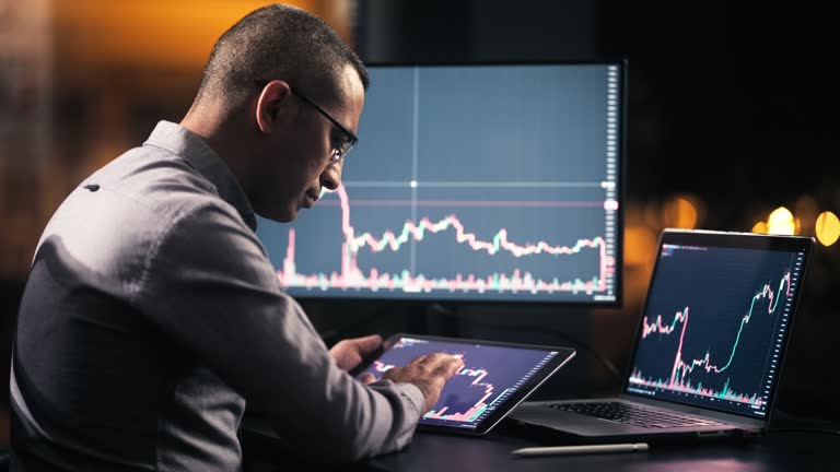 Man Checking His Stock Market Exchange Investment Using His Laptop Computer At Night