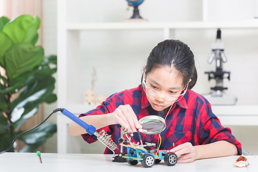 Asian child girl students build robotic cars, kids learn to program robot vehicles