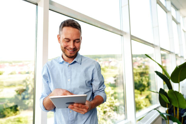 istock Modern businessman using digital tablet while standing near window in his office 1783325010
