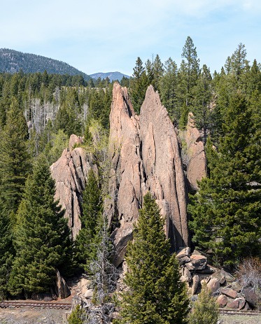 Dramatic vertical rock formation in the Boulder Batholith is probalby the result of fractures that formed as the intruding granite cooled. Abandoned railroad track at base of formation. Homestake Pass, Deerlodge National Forest, Montana, USA.