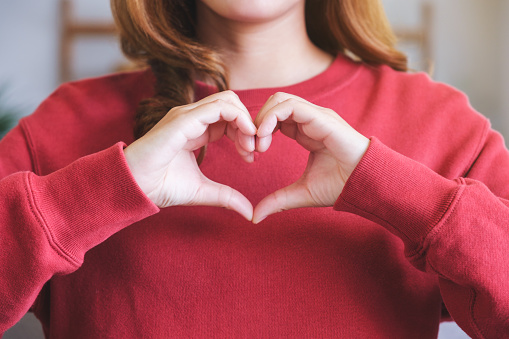Closeup image of a woman making heart hand sign