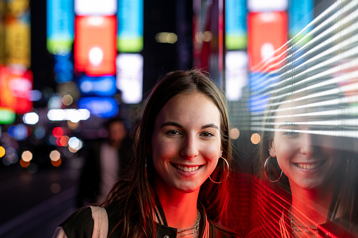 Young beautiful girl walking in Times Square at night. New York City, Manhattan