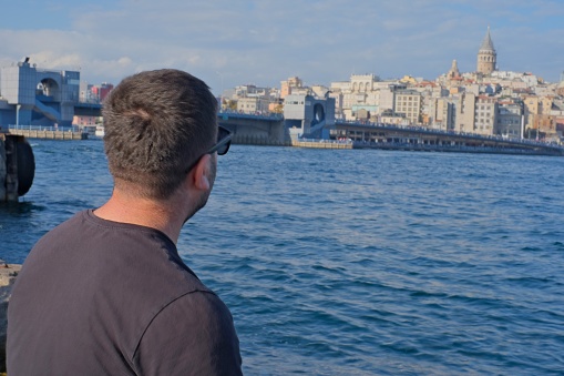Man looking towards Galata Tower on Eminönü beach, watching the magnificent view of Istanbul