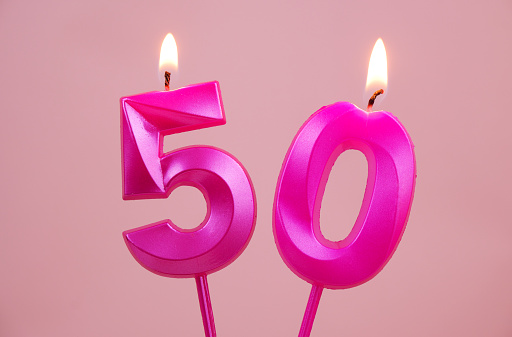 Pink birthday candles with burning on pink background. Number 50.
