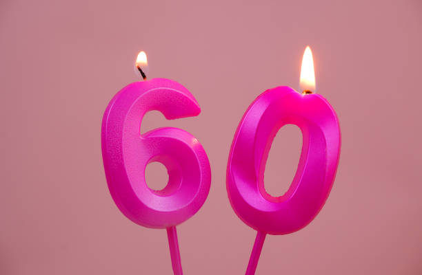 istock Pink birthday candles burning on pink, number 60. 1783417598
