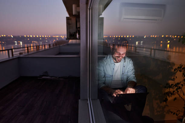 istock Happy man using laptop by the window at night. 1783424206