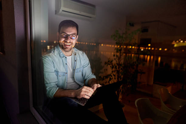 istock Happy man using laptop while relaxing by the window at night. 1783424781