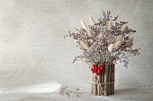 Authentic composition with viburnum berries and dried flowers in a vase.