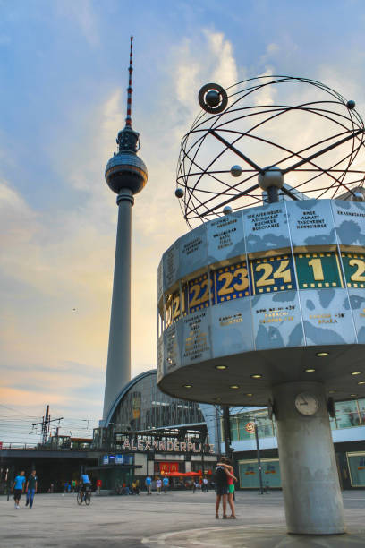 Berlin, Germany - July 2010: View of World Clock (Weltzeituhr) during sunset at Alexanderplatz with Berlin TV tower (Fernsehturm) and train station and clouds in blue sky background.