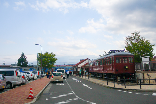 Fujikawaguchiko, Japan - May 2014: View of Mount Fuji and train museum and car parking lot from Kawaguchiko station with clouds in blue sky background.