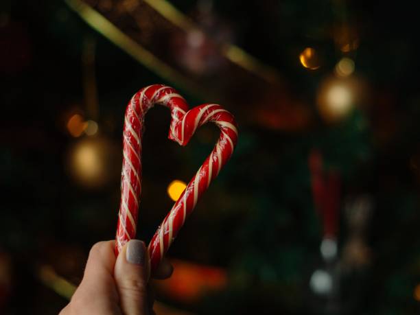 istock New Year's candy canes on a cozy blurred Christmas tree background with lights. candies and gifts for Christmas. New Year's Eve 1783473468