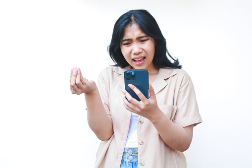 angry asian woman using smartphone with curled finger wearing casual clothes isolated on white background, upset female reading bad news in social media